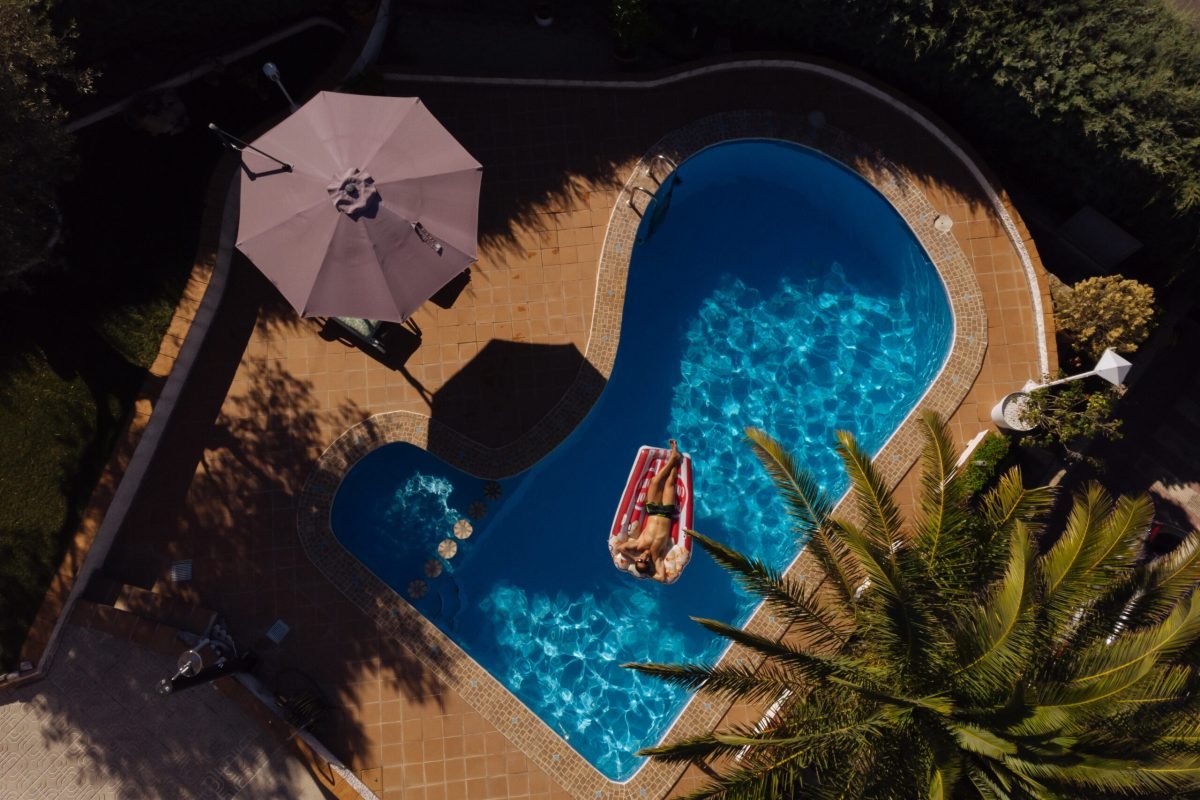 from above a man on beach mat in swimming pool of a villa house in a sunny day