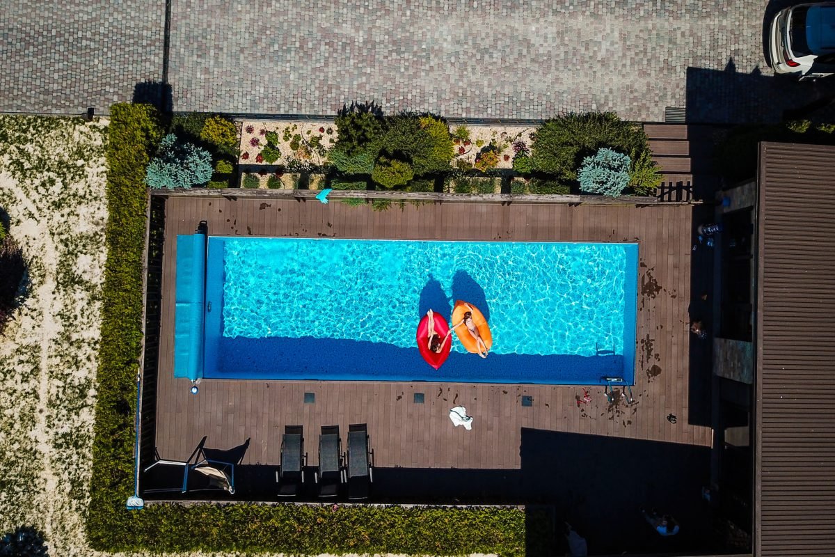 Two girls are swimming in a pool on inflatable mattresses